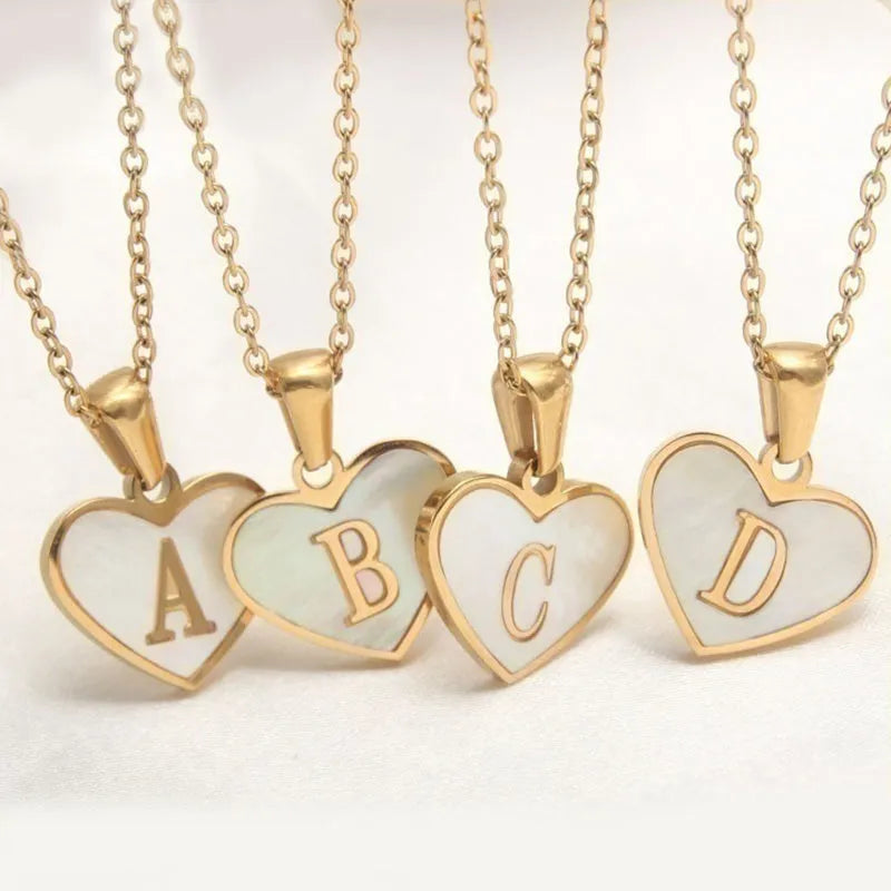 Gold-plated heart necklace with white shell pendant showing initial engraving on stainless steel chain