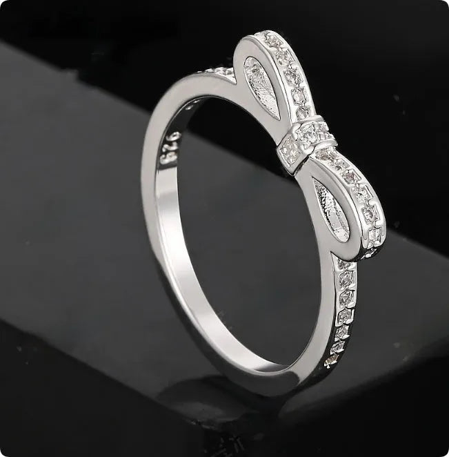 Silver couple style ring with bow shape decorated with rhinestone and zircon crystals.