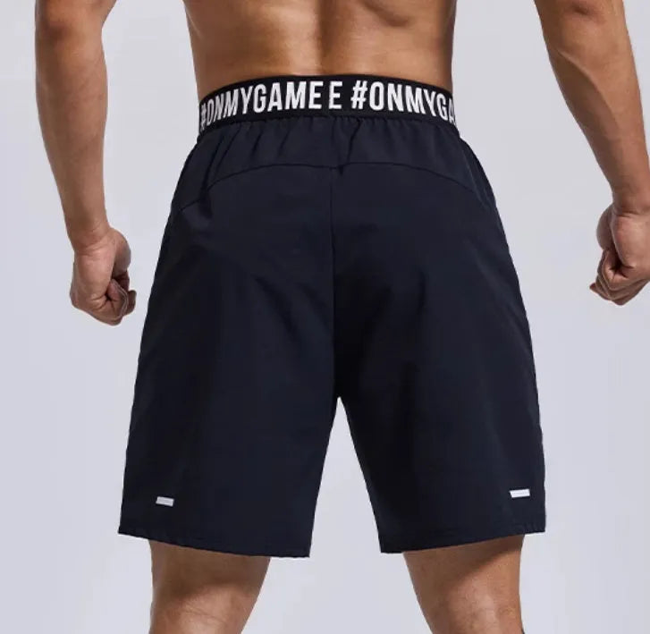 Men's loose black cropped sports shorts with an elastic waistband on a grey background