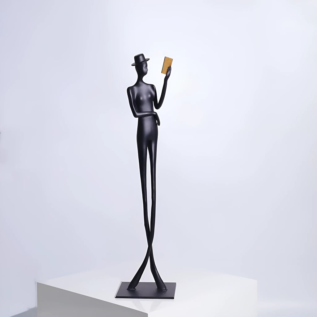 Black cast aluminium sculpture of a woman reading, modern minimalist desk decor.