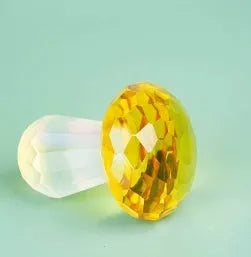 Colourful geometric crystal mushroom decoration in transparent, green, red, or yellow on a white background.