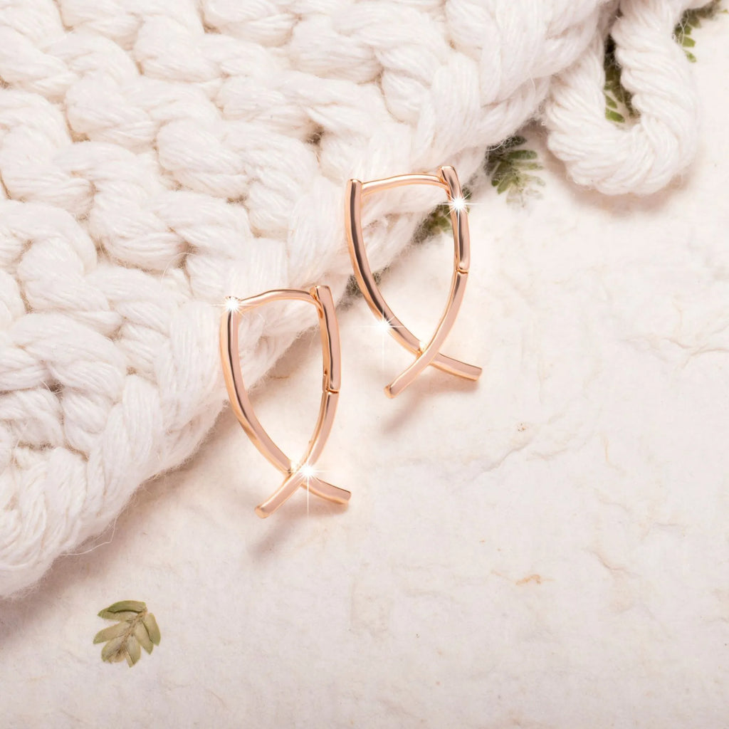 A pair of rose gold-coloured copper earrings in a detailed cross shape.