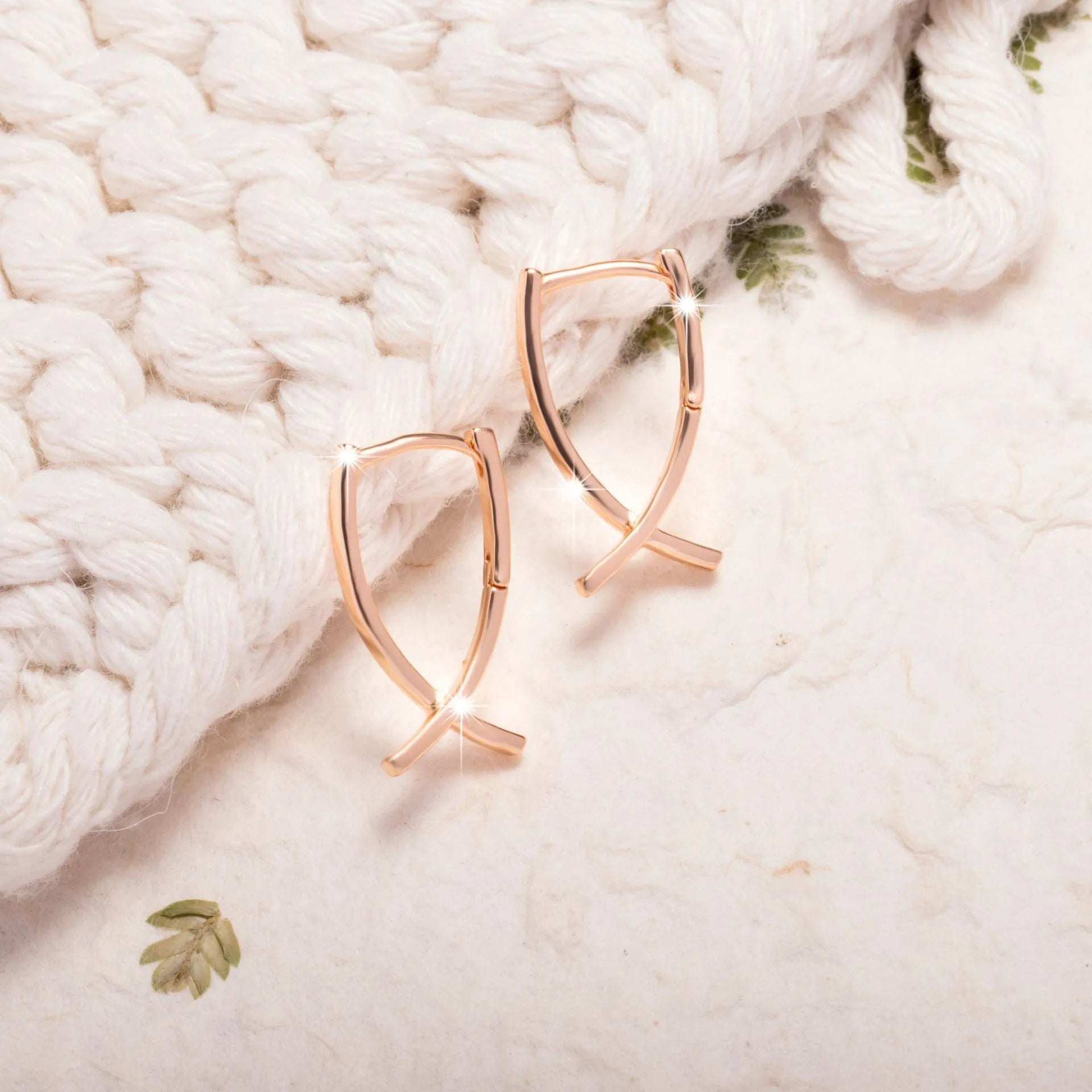 A pair of rose gold-coloured copper earrings in a detailed cross shape.