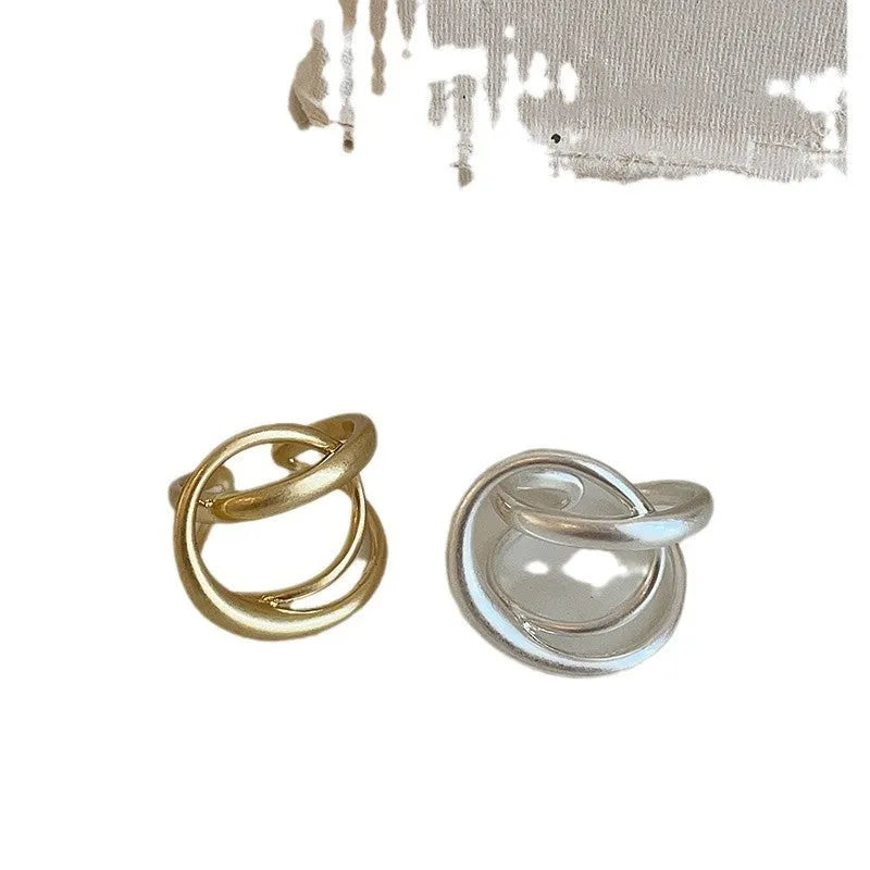 Geometric open ring for women with 3D interlaced matte metal design, shown in gold plating.