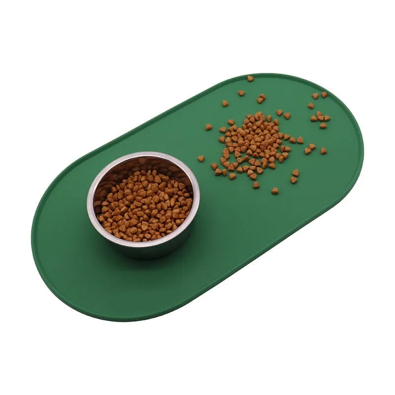 Silicone cat feeding placemat in beige colour, shown under food and water bowls on a kitchen floor.