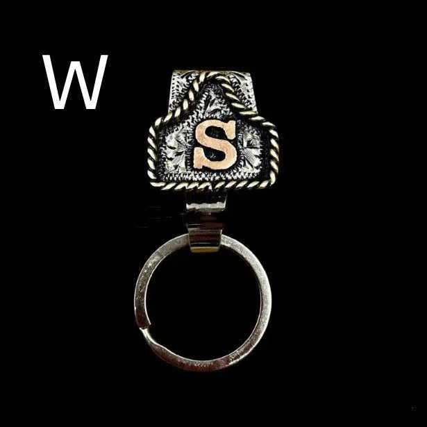 Handmade metal cow tag belt keychain showing one of 26 colour options, each marked with a different alphabet letter.