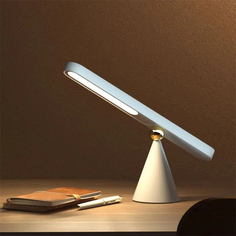 White geometric desk lamp with touch control and magnetic base on a wooden table.