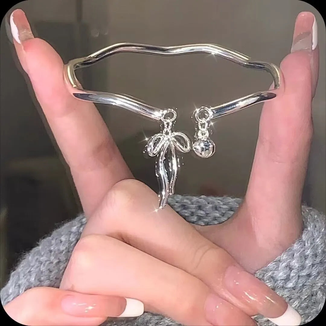 Silver adjustable bracelet with bow detail and bell opening clasp on wrist