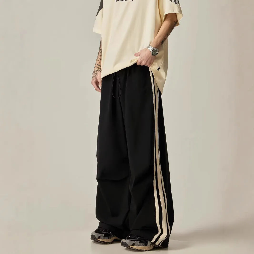 Black men's wide-leg high-waist climbing trousers laid flat, showing straight cut and polyester fabric.