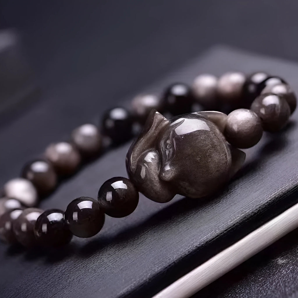 Close-up of black obsidian fox charm bracelet with 8mm polished bead on adjustable cord.