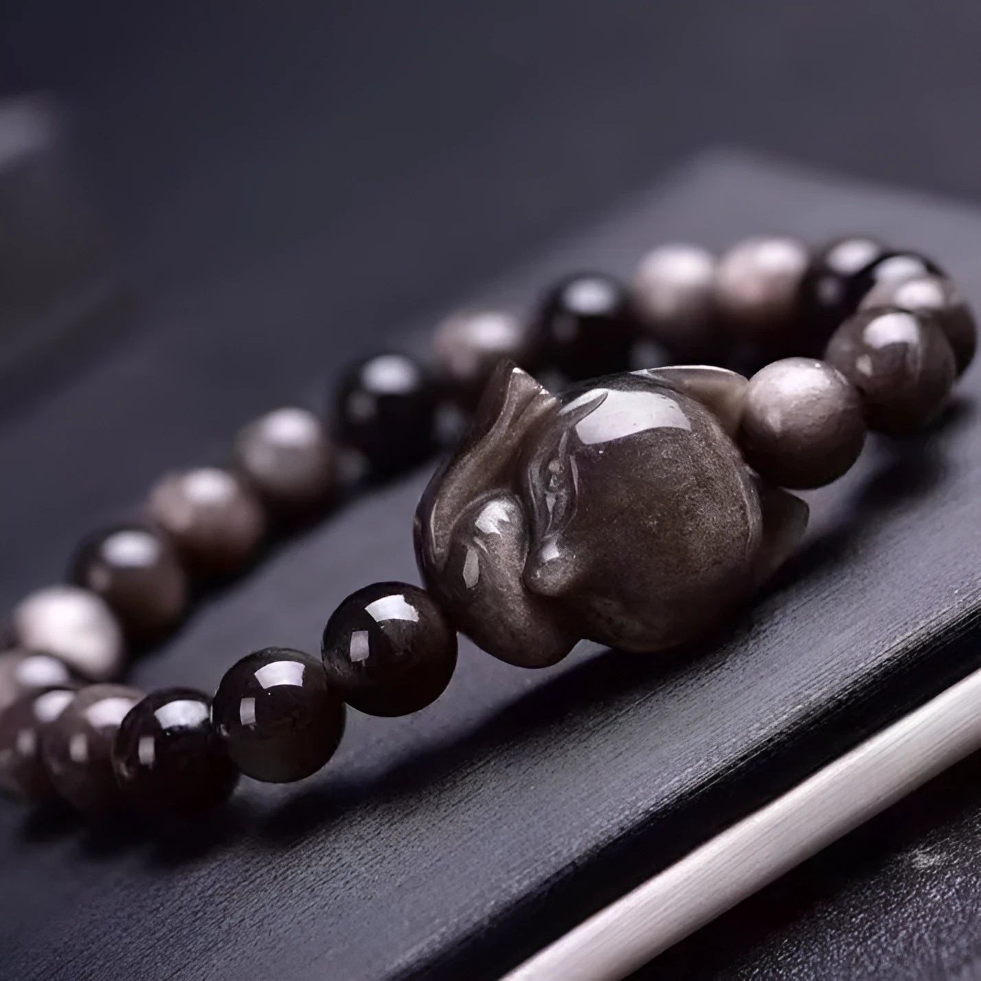 Close-up of black obsidian fox charm bracelet with 8mm polished bead on adjustable cord.