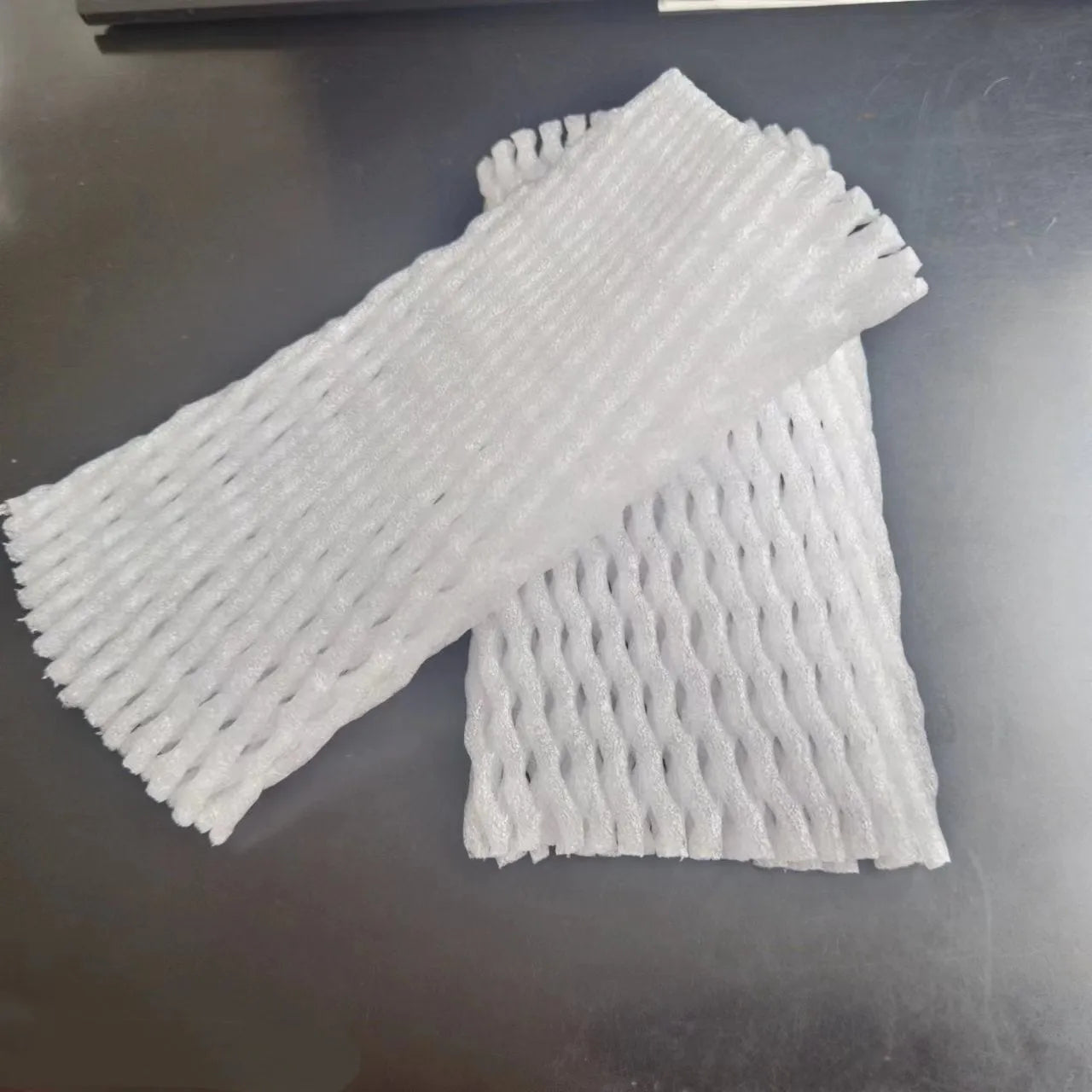 White foam protective net sleeves for fruit in assorted sizes on a table.
