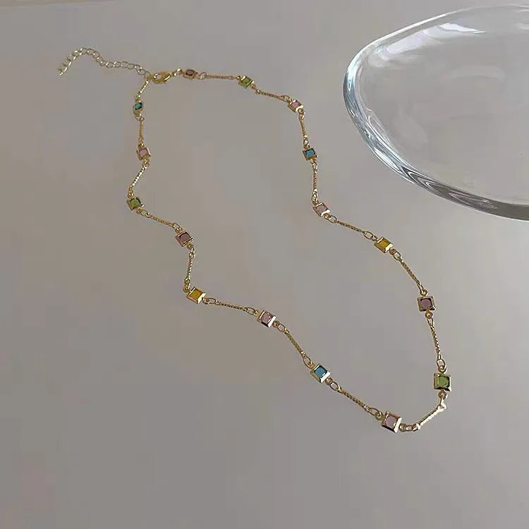 Fine geometric clavicle chain necklace with square artificial crystal links in gold or white K plating.