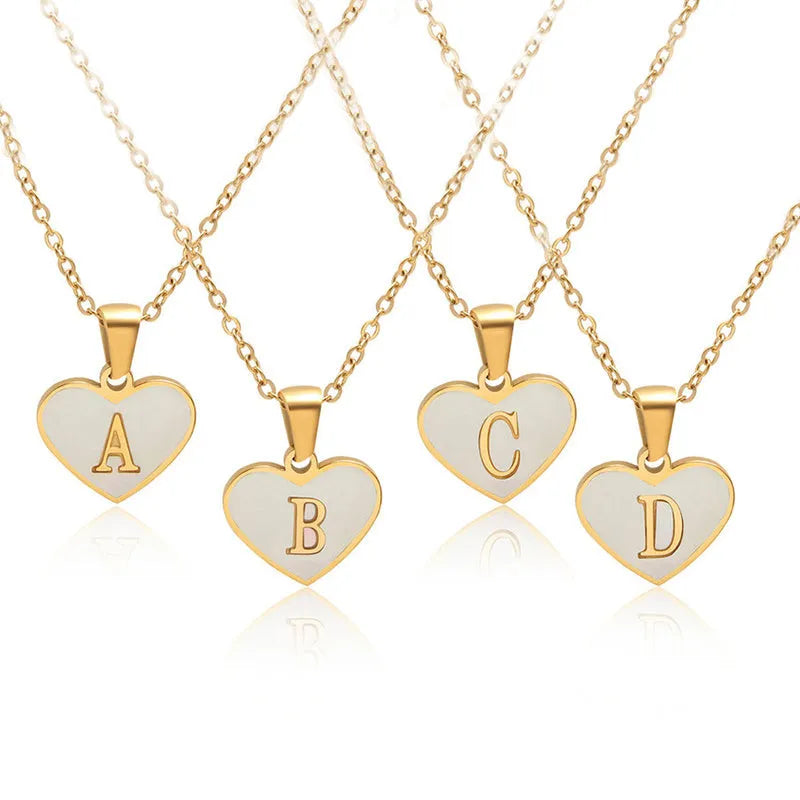 Gold-plated heart necklace with white shell pendant showing initial engraving on stainless steel chain