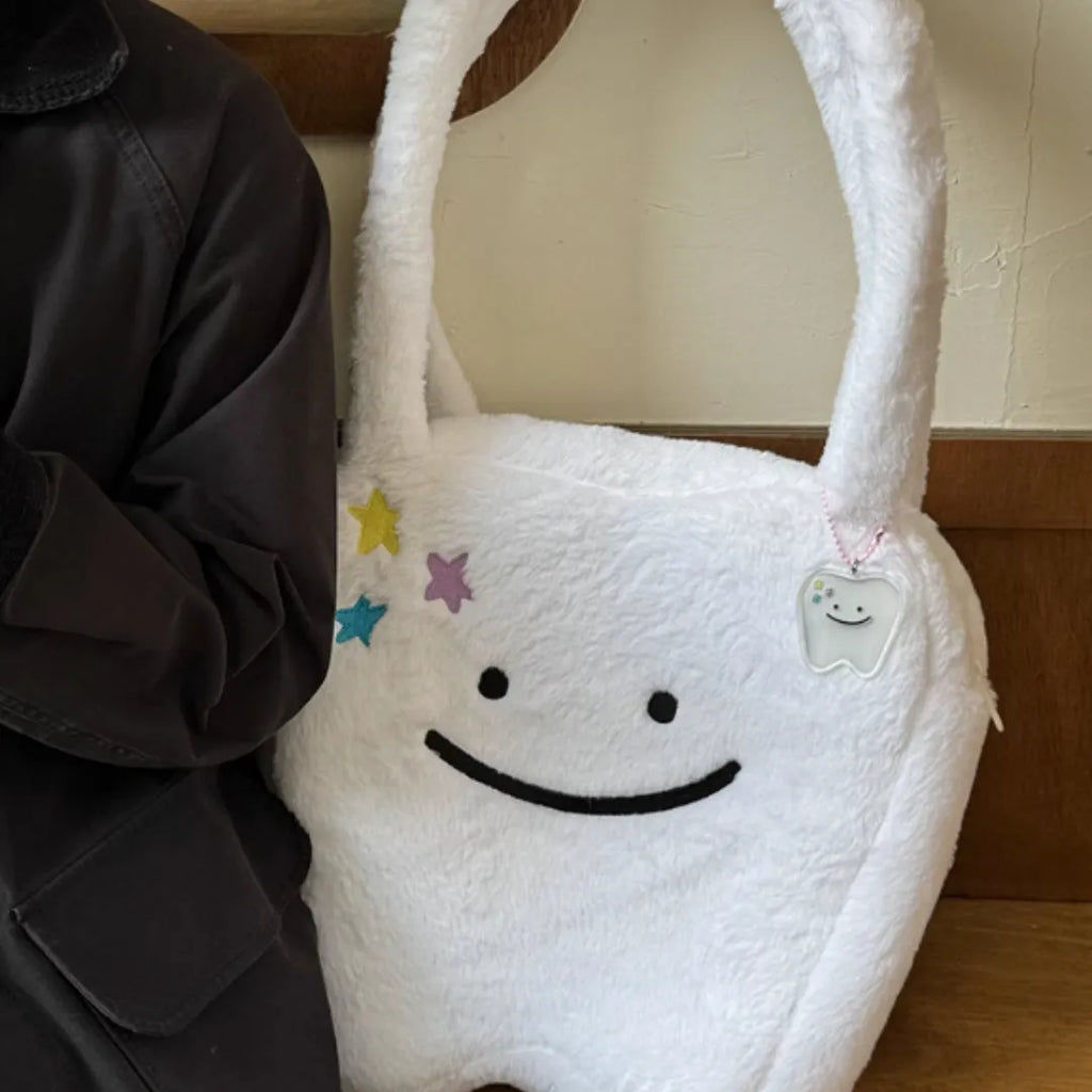 White plush large tooth shoulder tote bag with crossbody strap and zip closure.