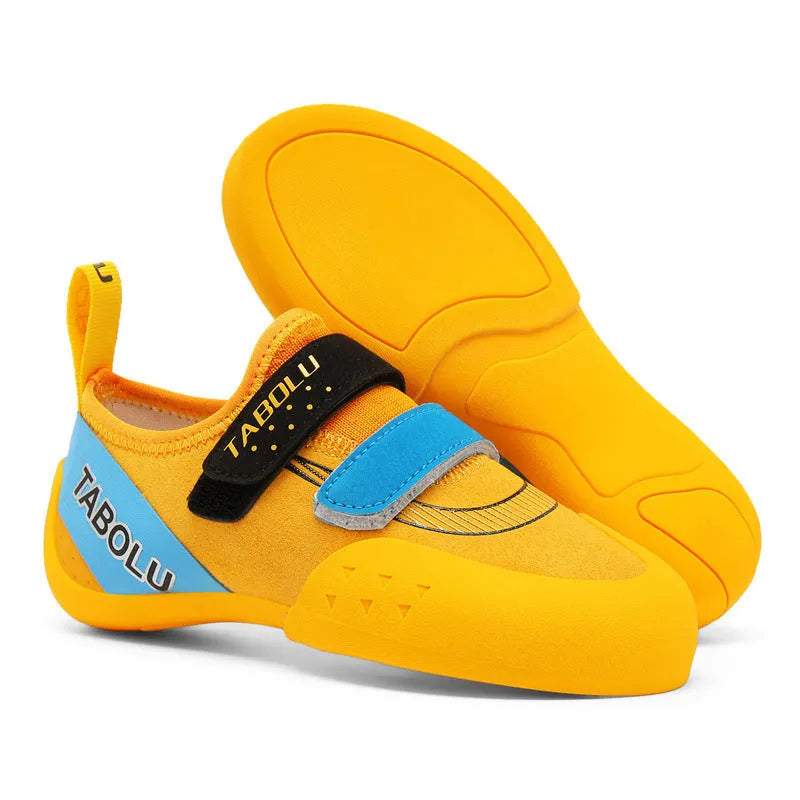 Black and red beginner rock climbing shoes with velcro strap and rubber sole on a climbing hold.