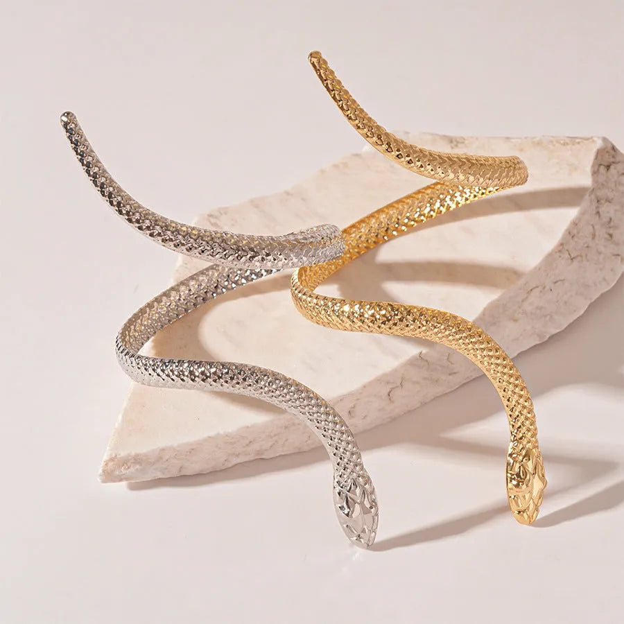 Gold tone snake-inspired bracelet and ring set with exaggerated twisted winding design on white background