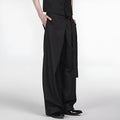 Black loose fit straight leg trousers with a single pleat and adjustable waistband on a hanger.