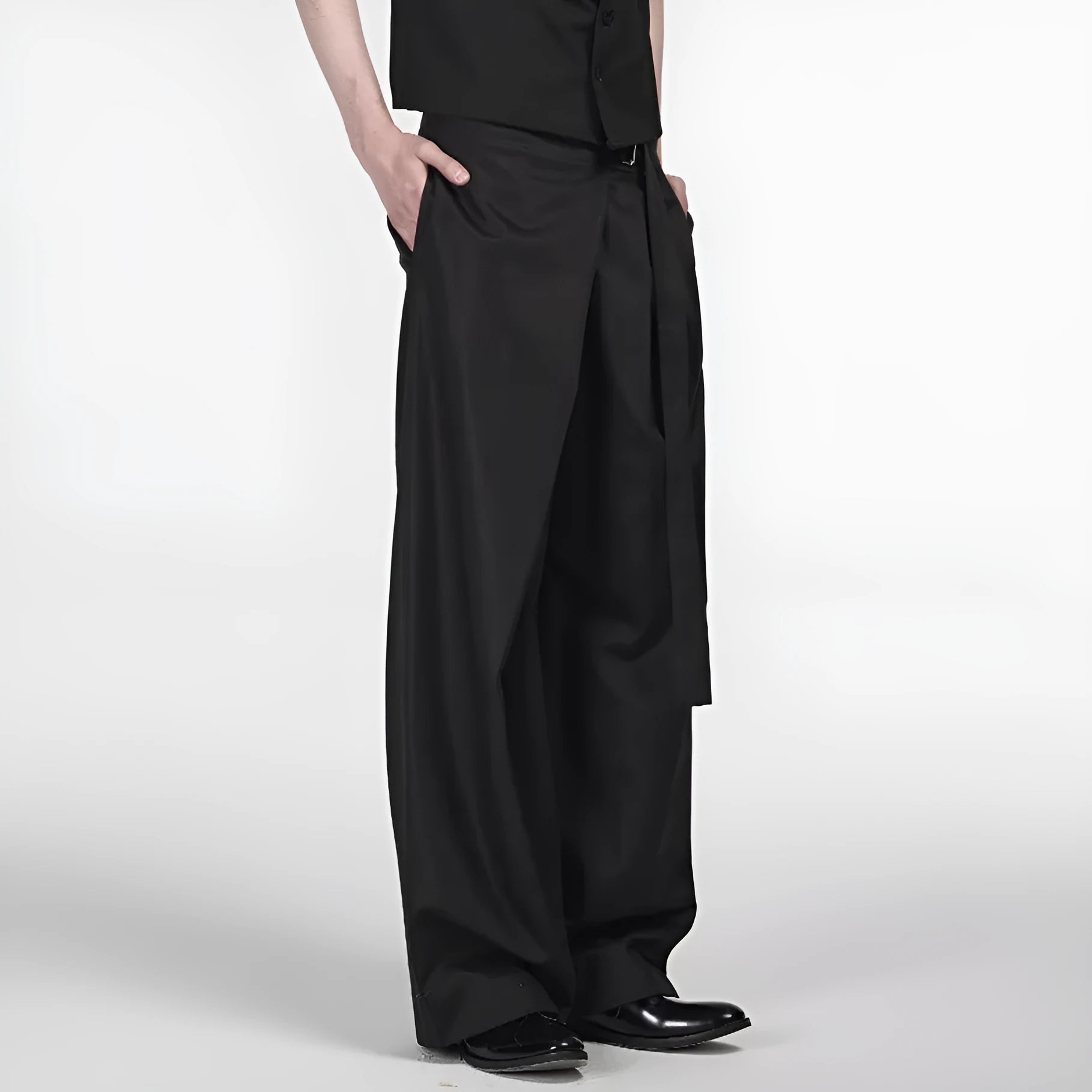 Black loose fit straight leg trousers with a single pleat and adjustable waistband on a hanger.