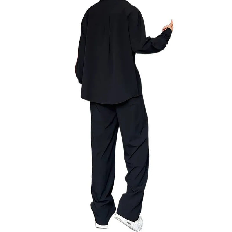 Man wearing a black slim fit long sleeve polo shirt and matching trousers from a casual two-piece set.