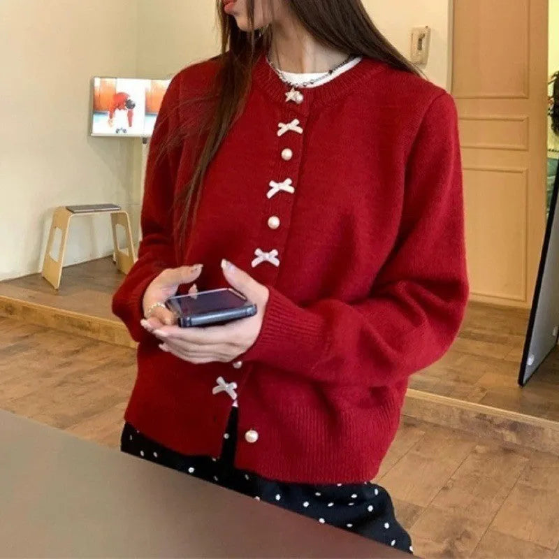 Women's light blue acrylic cardigan sweater with pearl buttons and a decorative bow detail.