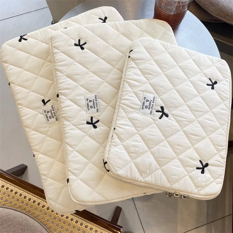 White nylon laptop bag with embroidered rhombus pattern and fabric bow, shown alongside black, light blue, and light pink colour options.