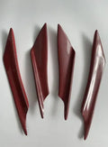 Set of four carbon fibre pattern bumper blade spoilers for car modification on a black background.