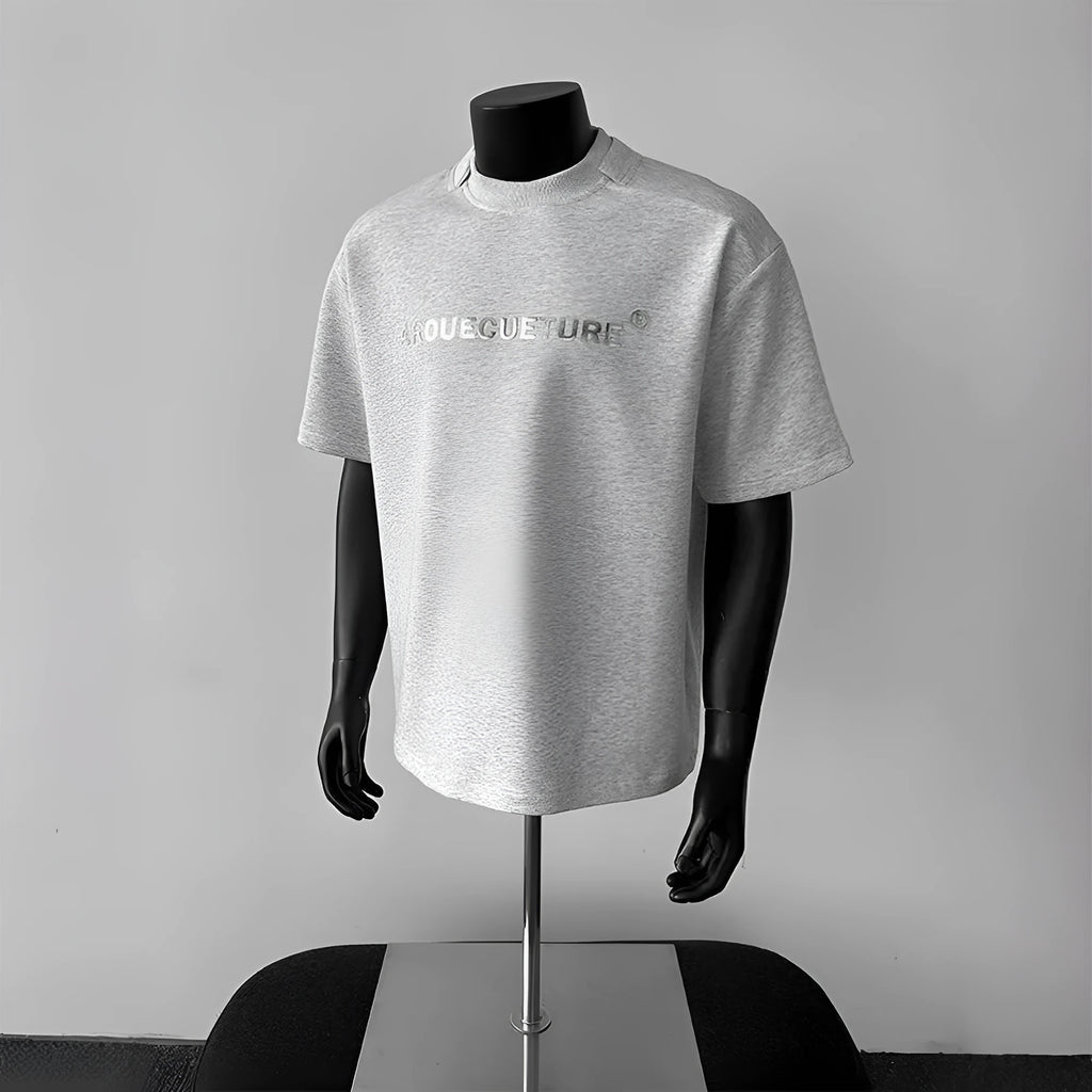 Man wearing a loose grey short sleeve cotton shirt with a letter print design.