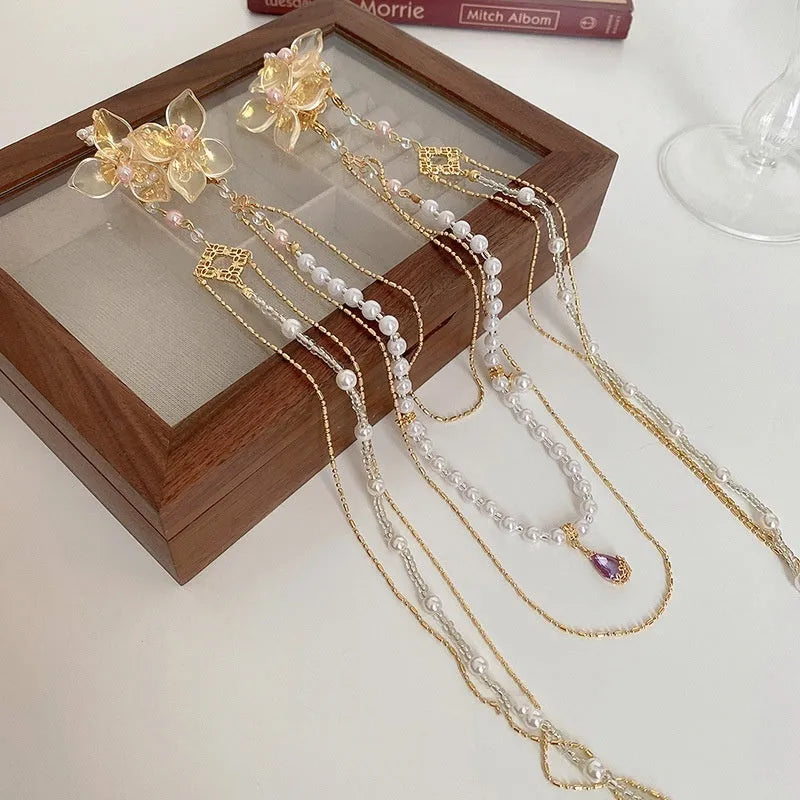 Close-up of a women's floral hairpin with white pearl, clear diamond accents, and a long gold tassel.