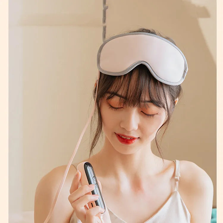 Pink or green portable steam sleep massage goggles with USB cable on a grey background.