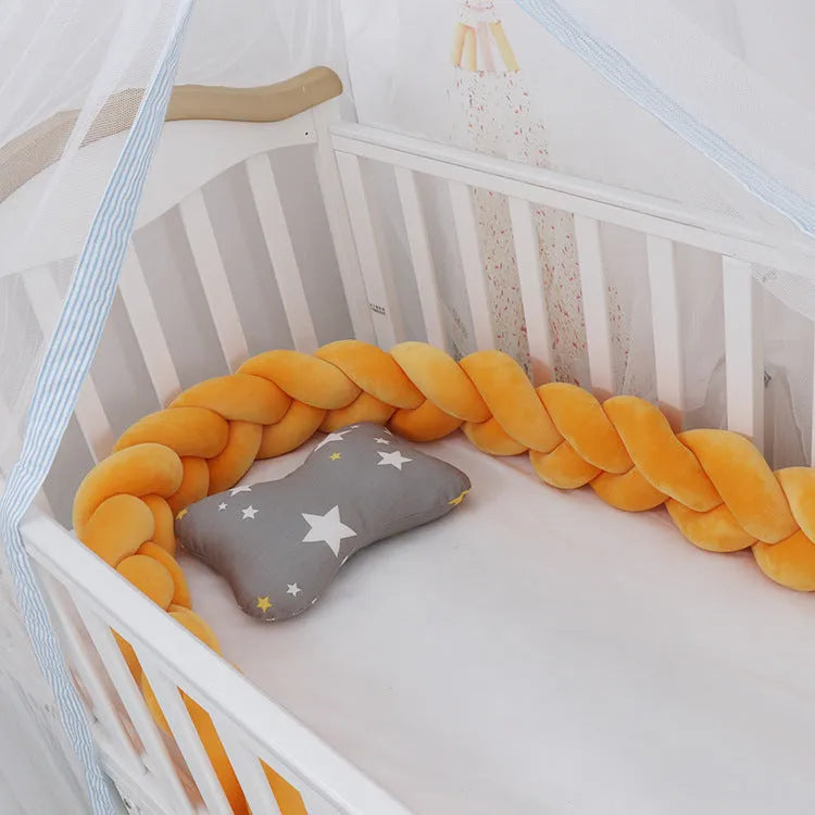 Braided knot pillow cushion bumper for infant crib in spandex velvet, shown in a light colour.