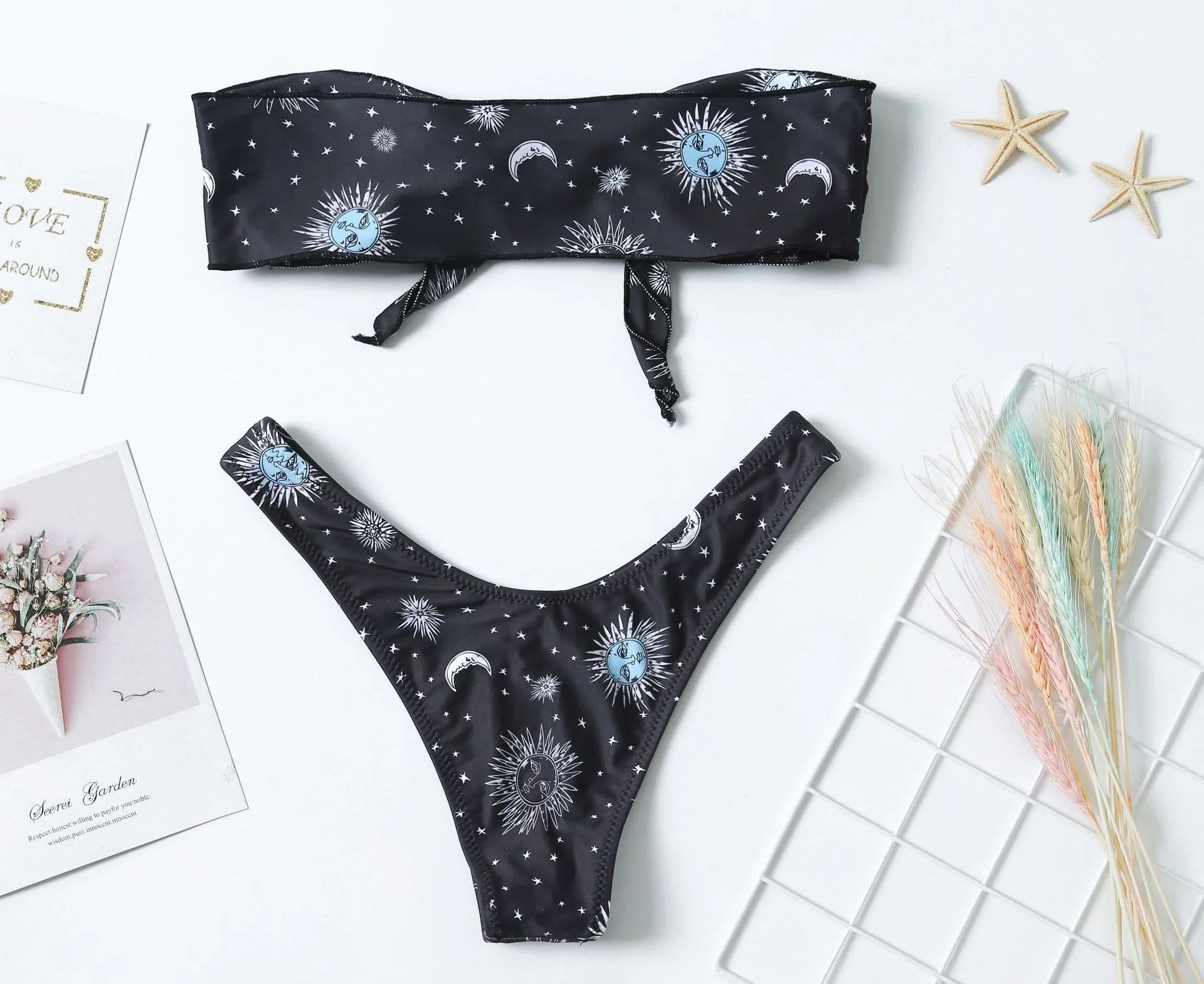 Black one-piece swimsuit with a bikini print pattern, showing backless design.