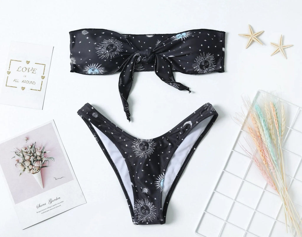 Black one-piece swimsuit with a bikini print pattern, showing backless design.