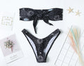Black one-piece swimsuit with a bikini print pattern, showing backless design.