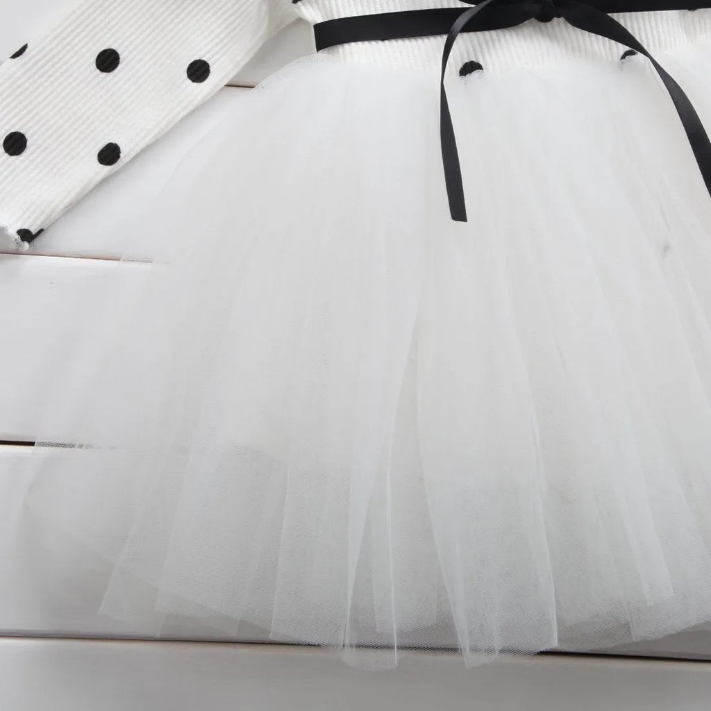 Baby girl wearing a long sleeve black tutu lace dress for a first birthday or christening event.