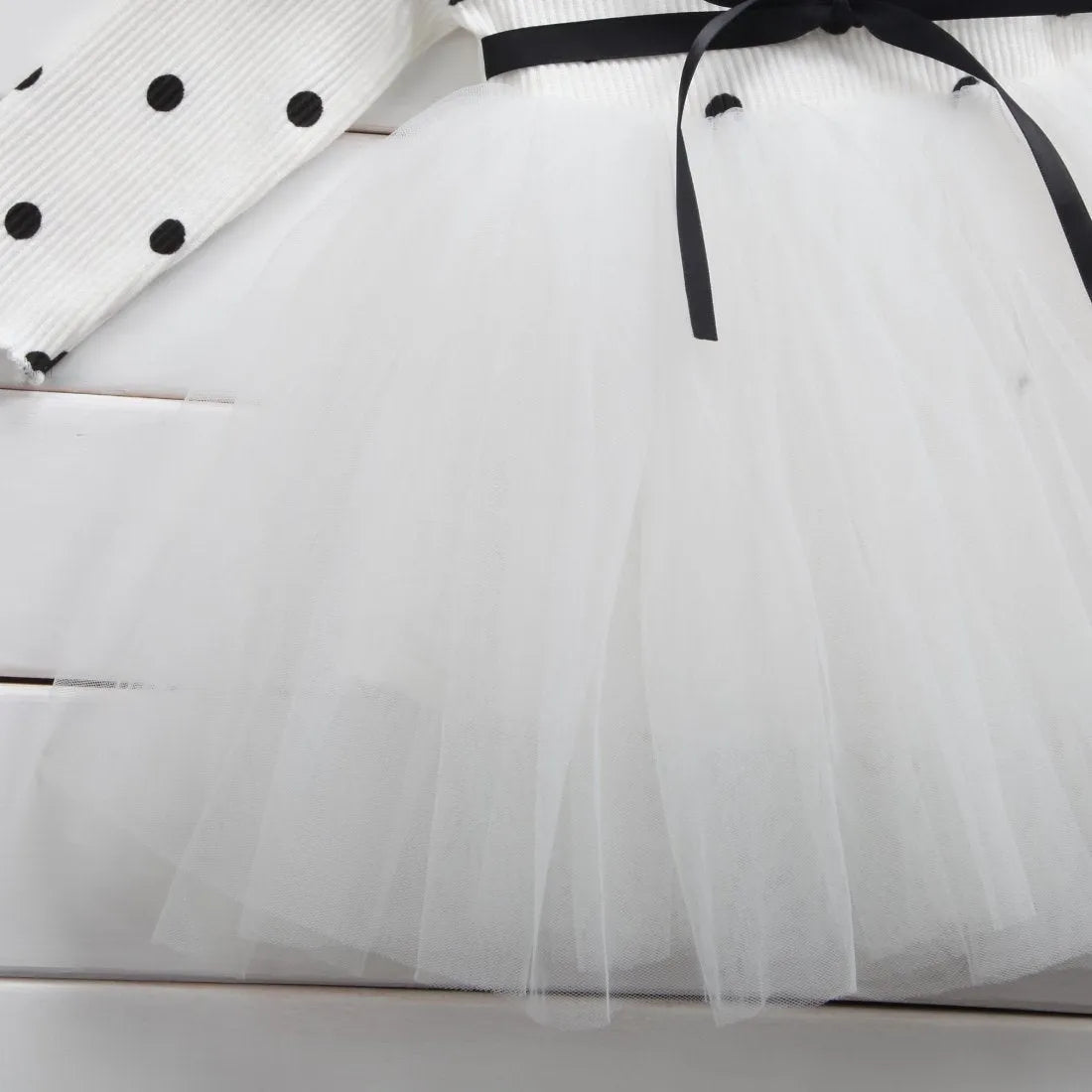 Baby girl wearing a long sleeve black tutu lace dress for a first birthday or christening event.