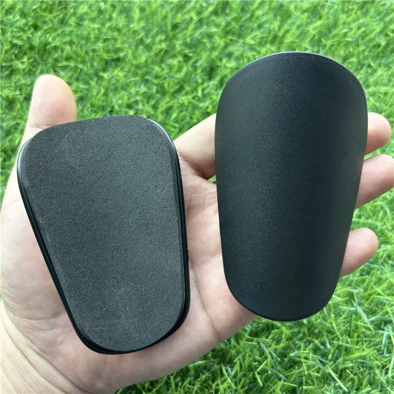 Pair of extra small black plastic football shin guards for junior players.