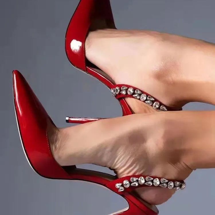 Women's black patent leather pointed toe high heel sandals with side rhinestones and an ankle strap.
