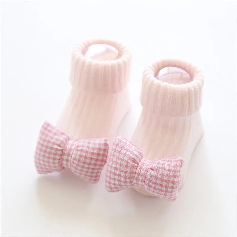 Cotton baby floor socks with non-slip soles in a pink bow print design.