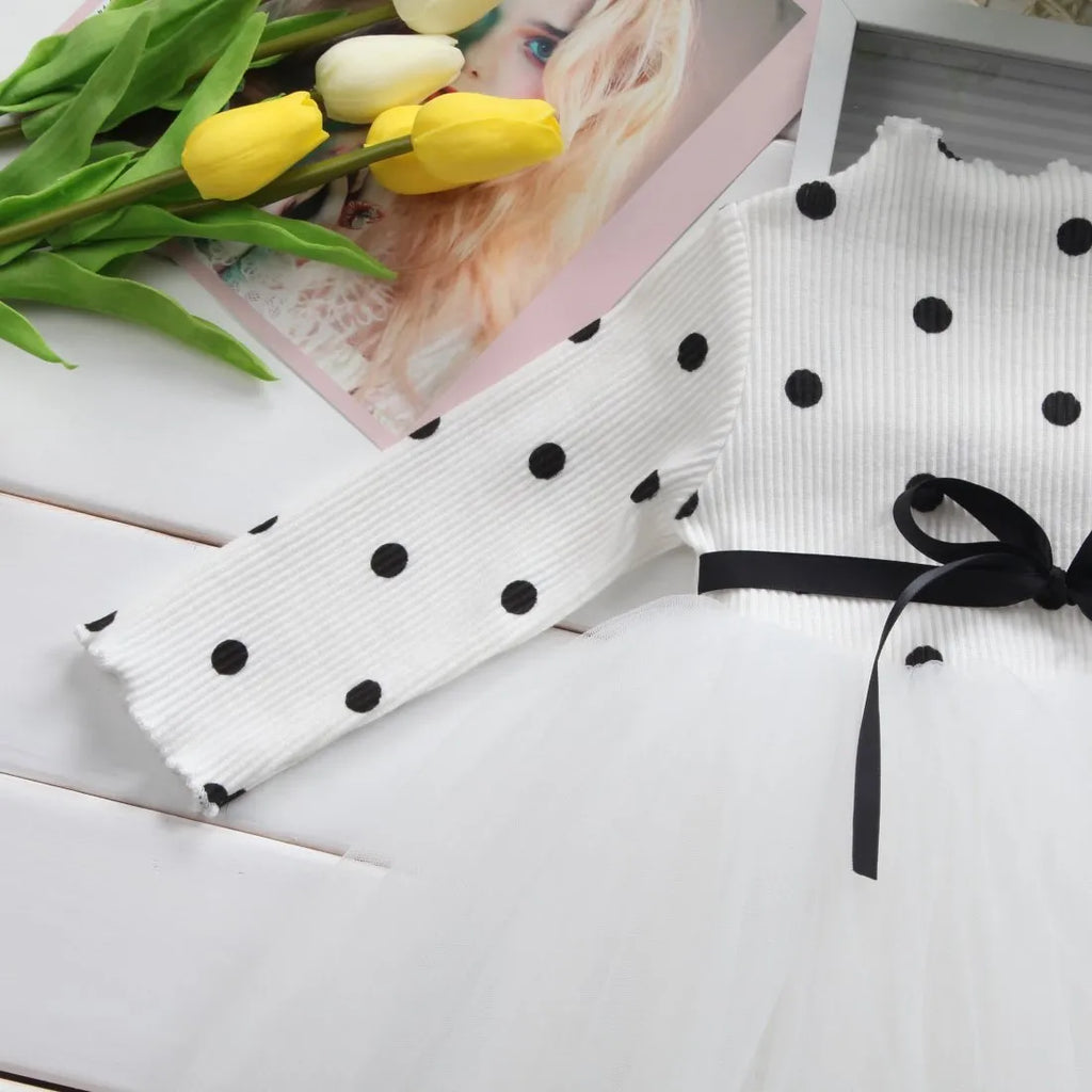 Baby girl wearing a long sleeve black tutu lace dress for a first birthday or christening event.
