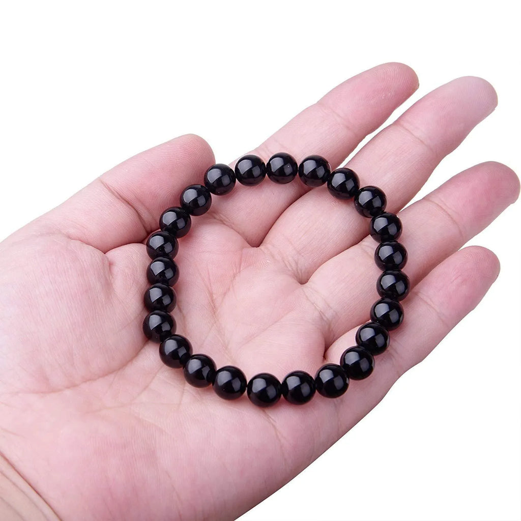 Black agate bracelet with geometric 8mm beads on a black elastic cord, laid flat.
