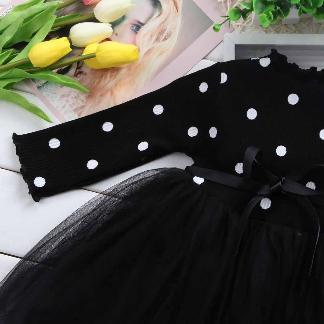 Baby girl wearing a long sleeve black tutu lace dress for a first birthday or christening event.