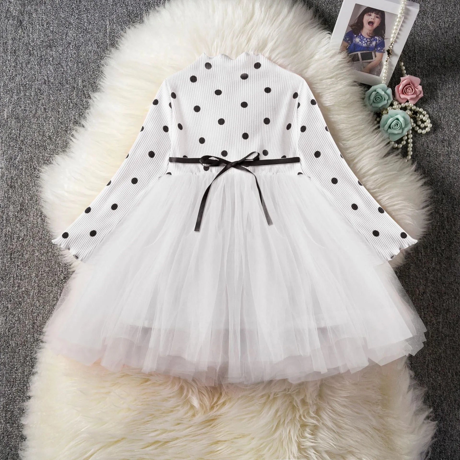 Baby girl wearing a long sleeve black tutu lace dress for a first birthday or christening event.