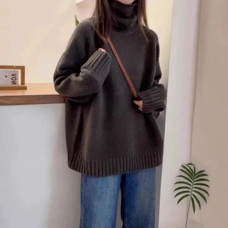 Women's loose grey turtleneck sweater with thick curling pile collar, worn in a casual setting.