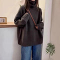 Women's loose grey turtleneck sweater with thick curling pile collar, worn in a casual setting.