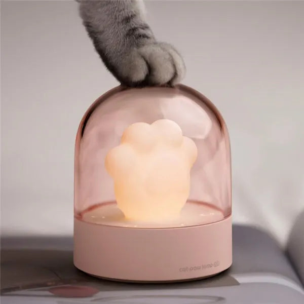 Grey cat paw shaped USB rechargeable night light with music box on a desk.