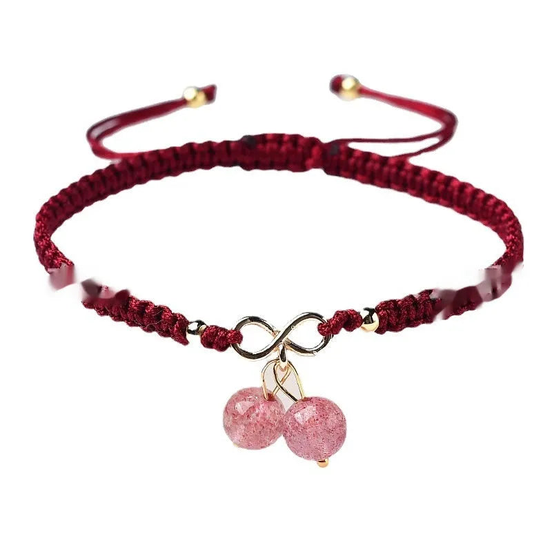 Close-up of a women's natural crystal bracelet with a detailed cherry charm in strawberry quartz colour.