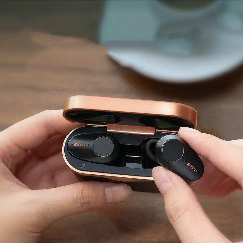 Black wireless Bluetooth headphones with charging case on a table.