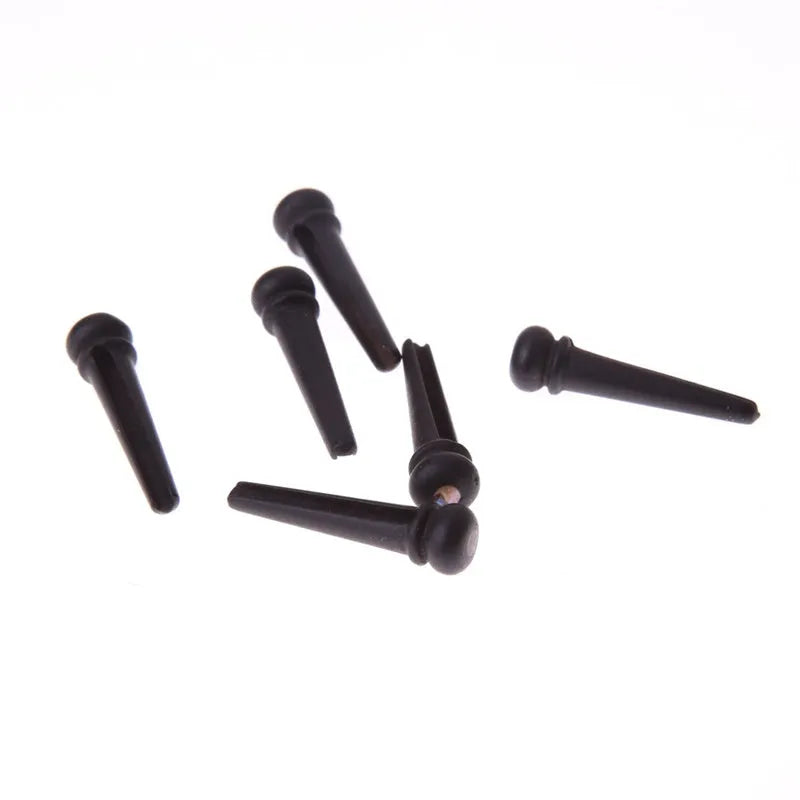 Six solid ebony guitar string nails with matt black finish for folk acoustic guitars.