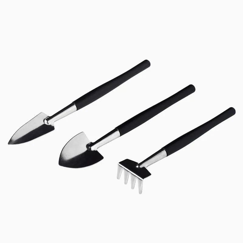 Black mini garden hand tools set for succulents with tweezers, shovels, watering bottle, brushes, and a grey cushion.